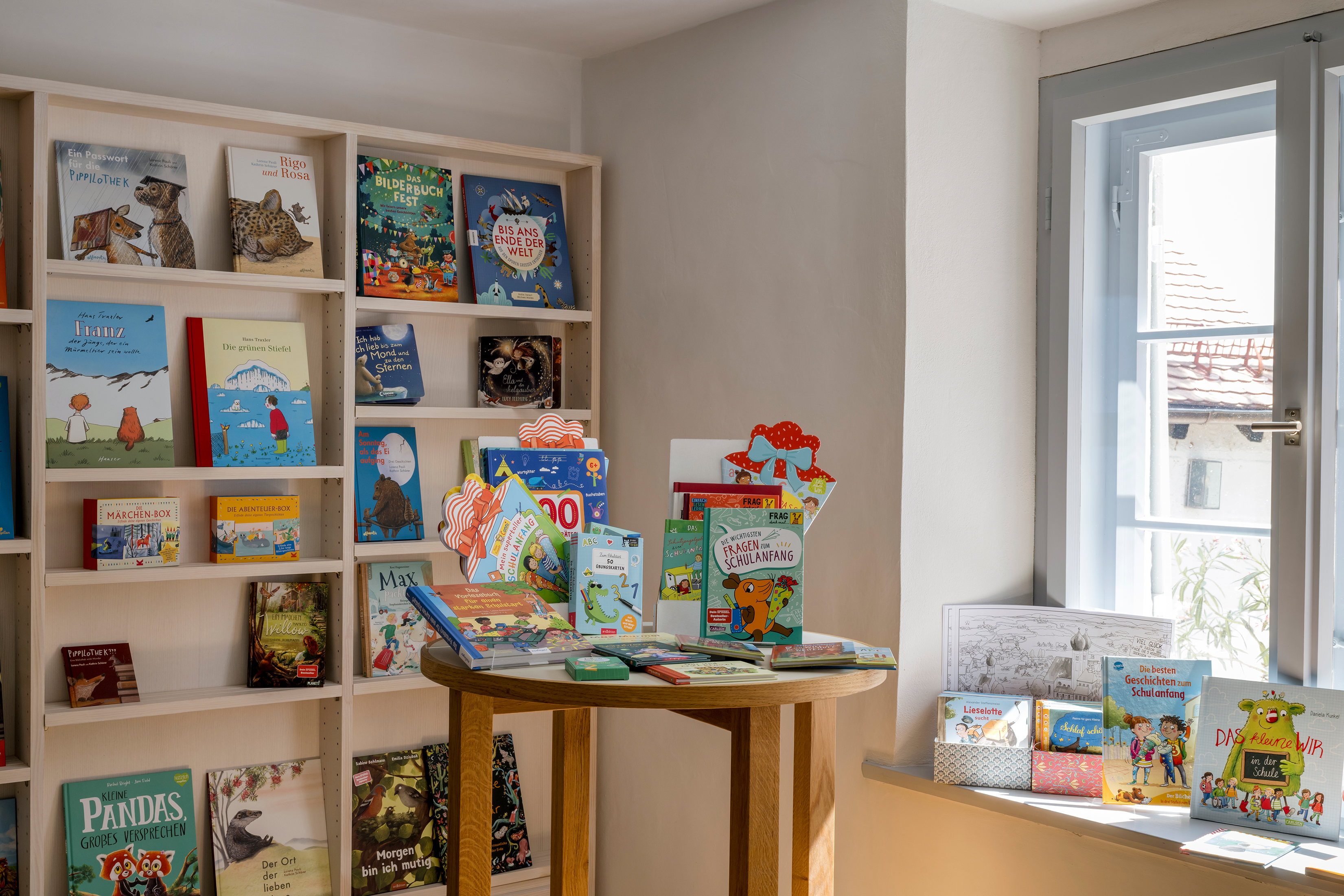 ... verschiedene Kinderbüchern Verschiedene Kinderbücher werden auf einem Stehtisch, einem Bücherregal und einem Fensterbrett präsentiert