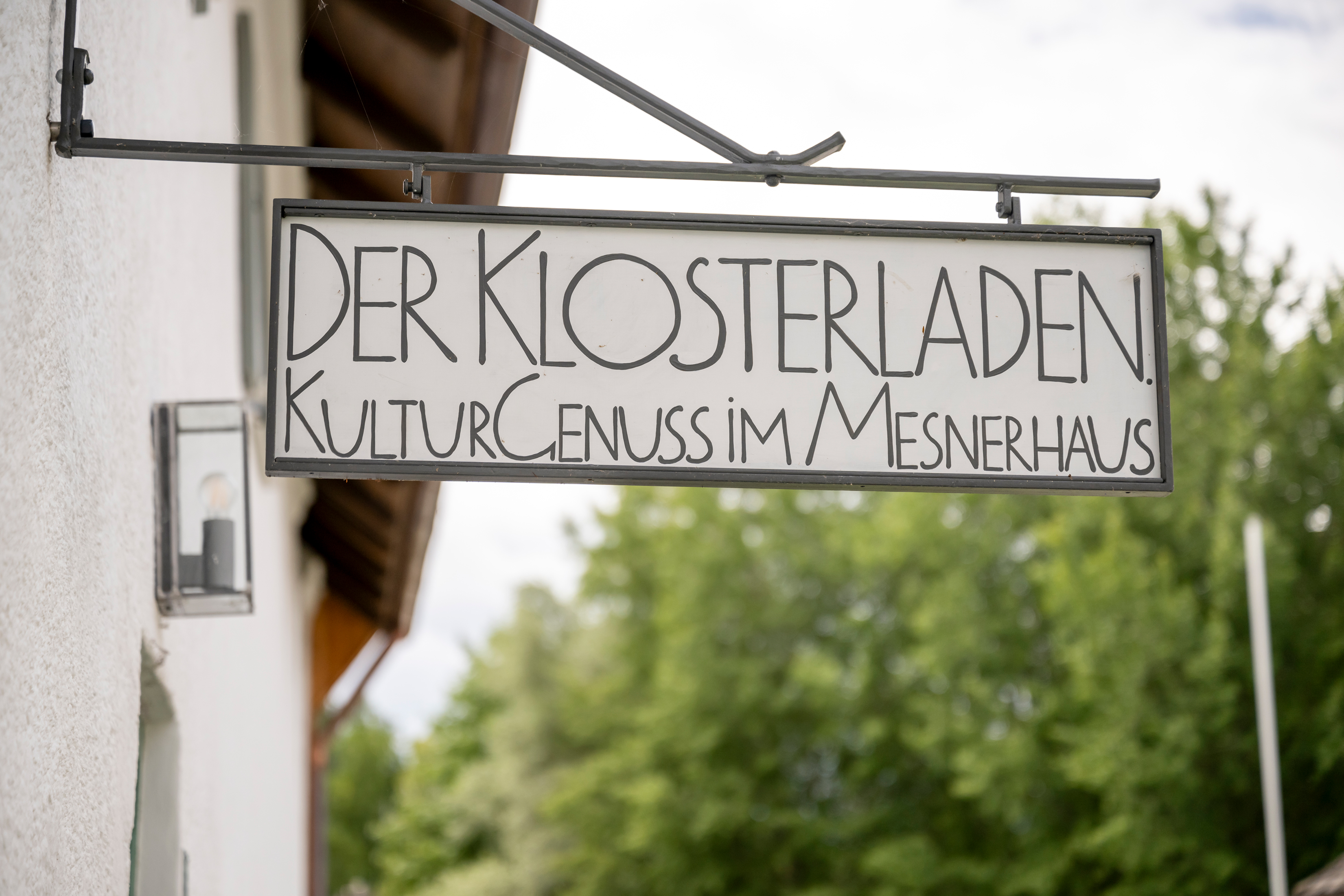 Aushängeschild am Mesnerhaus bei Kloster Seeon mit dem Schriftzug Der Klosterladen. KulturGenuss im Mesnerhaus