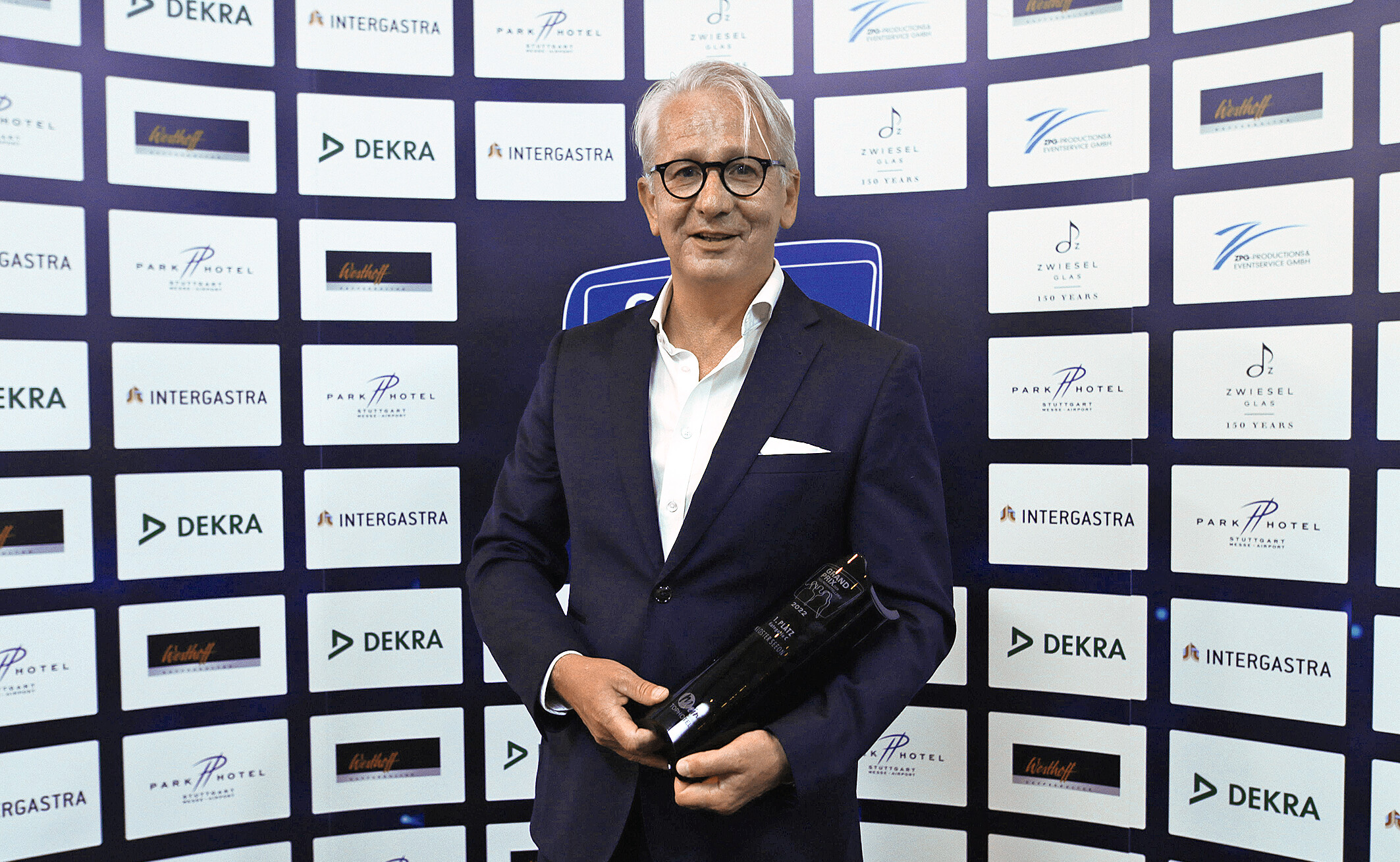 Gerald Schölzel mit der Siegertrophäe vor der Sponsorenwand im Parkhotel Stuttgart