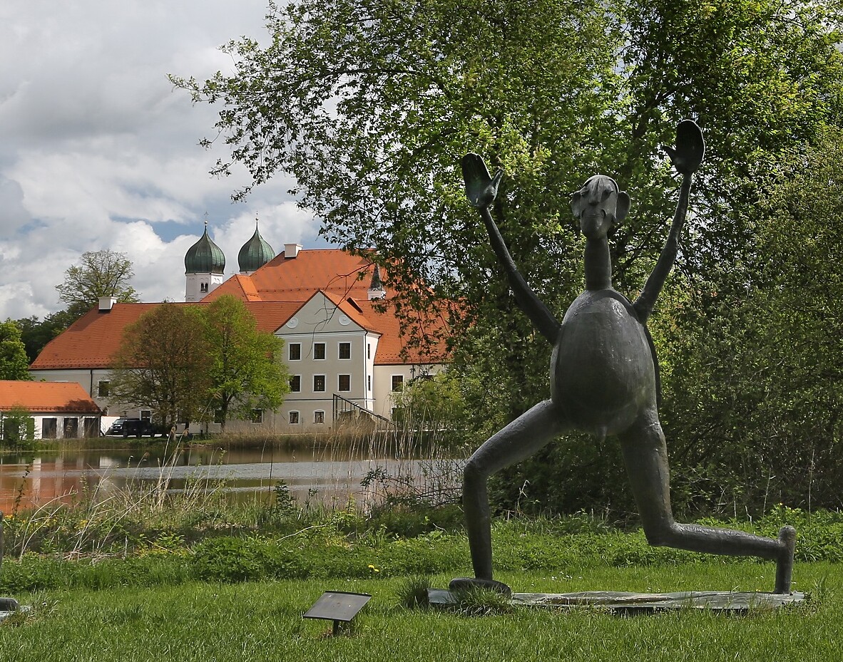 Bronzefigur mit erhobenen Händen von Heinrich Kirchner, im Hintergrund Kloster Seeon 