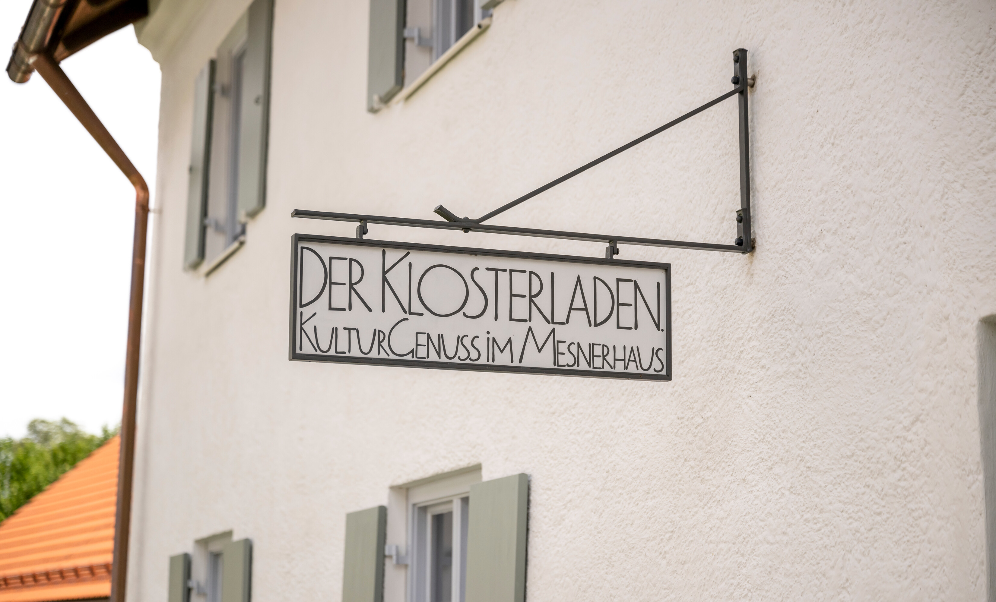 Das Schild über dem Eingang zum Klosterladen im Mesnerhaus, worauf steht: Der klosterladen. KulturGenuss im Mesnerhaus