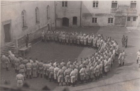 In hellen Uniformen gekleidete M&auml;ner versammeln sich U-f&ouml;rmig im Innenhof von Kloster Seeon. Schwarz-wei&szlig;-Fotografie.