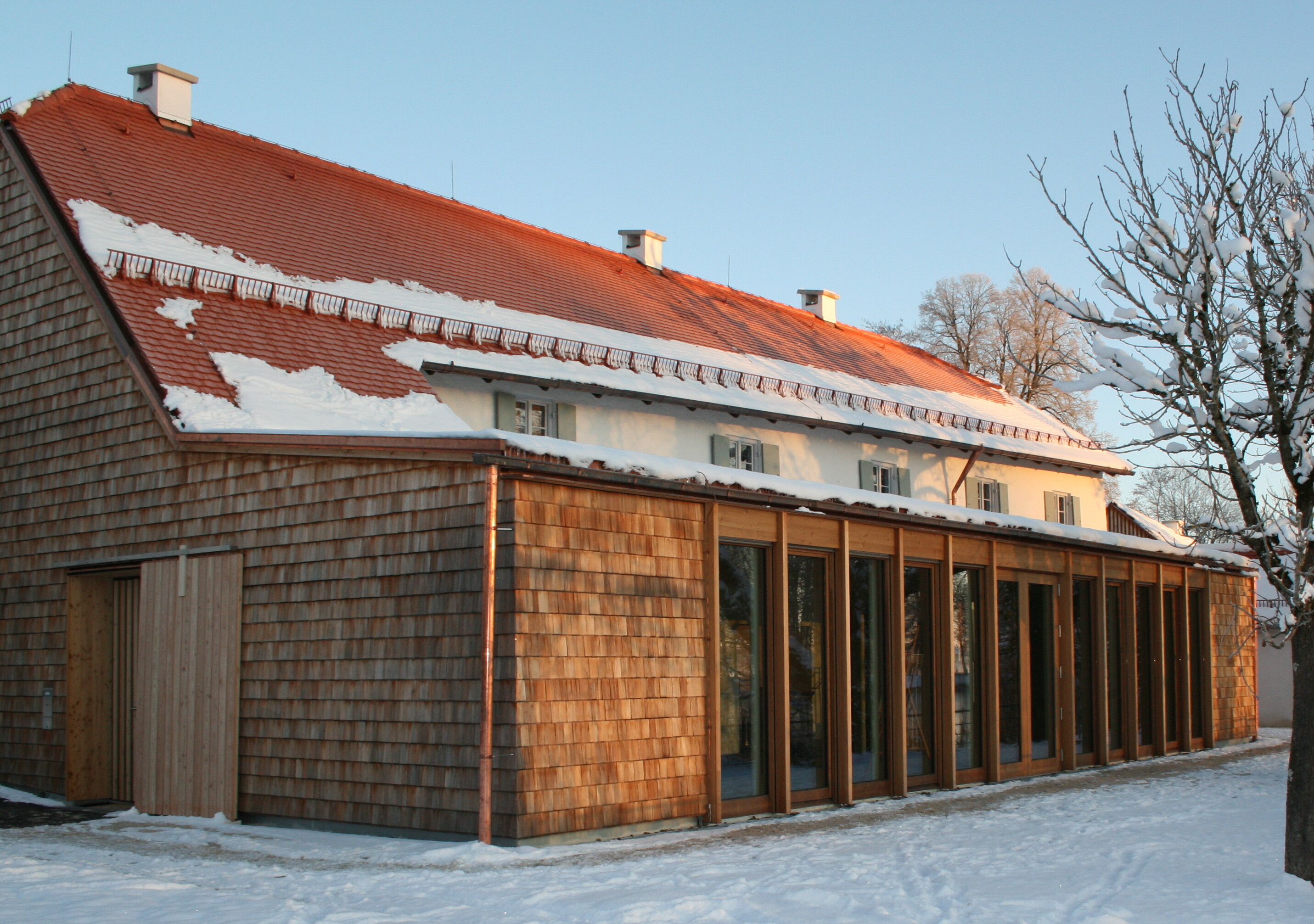 Ein mit Holzschindeln bekleidetes Haus mit vielen Fenstern im Winter