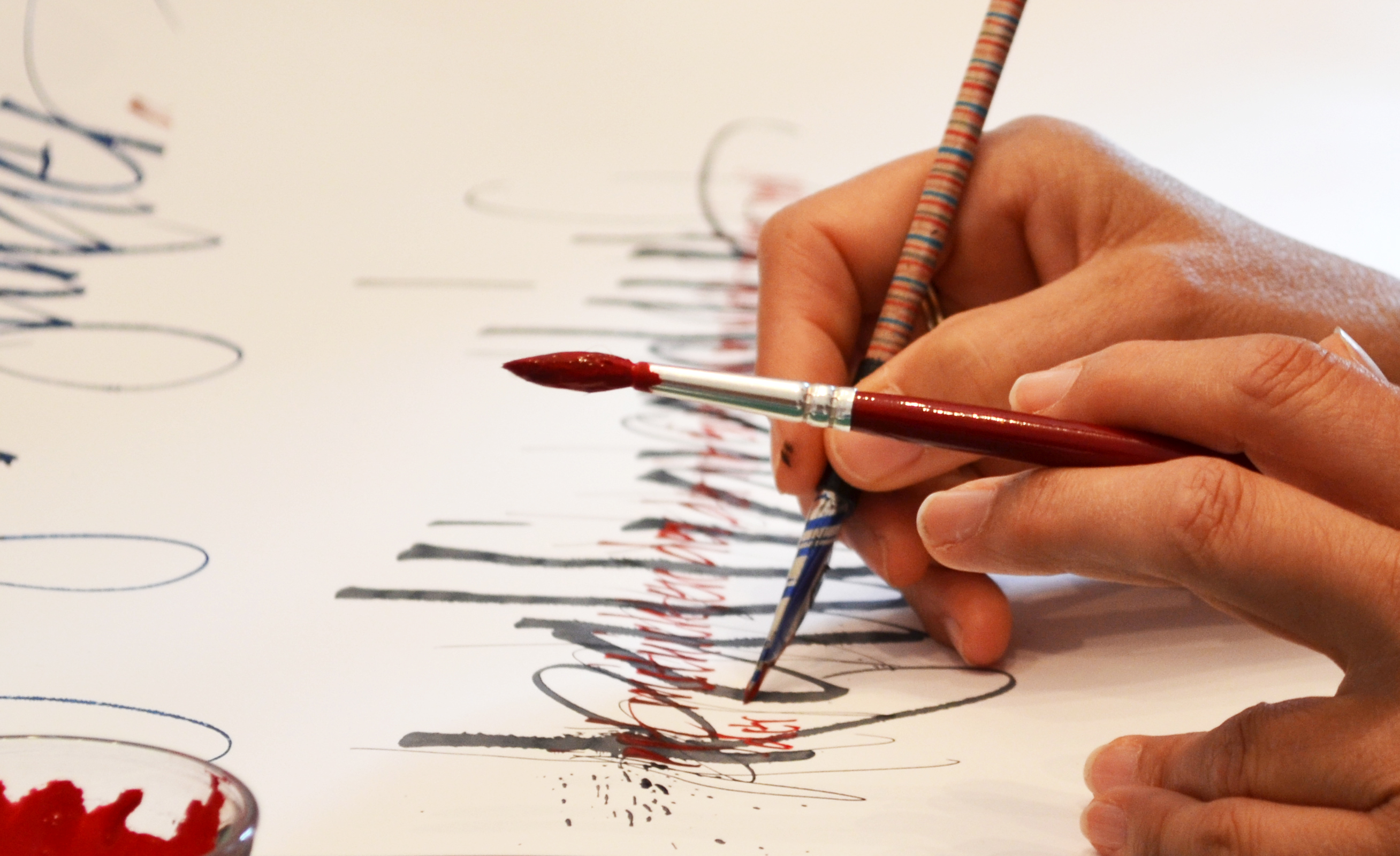 Hände malen und schreiben auf weißem Papier mit Feder und Pinsel