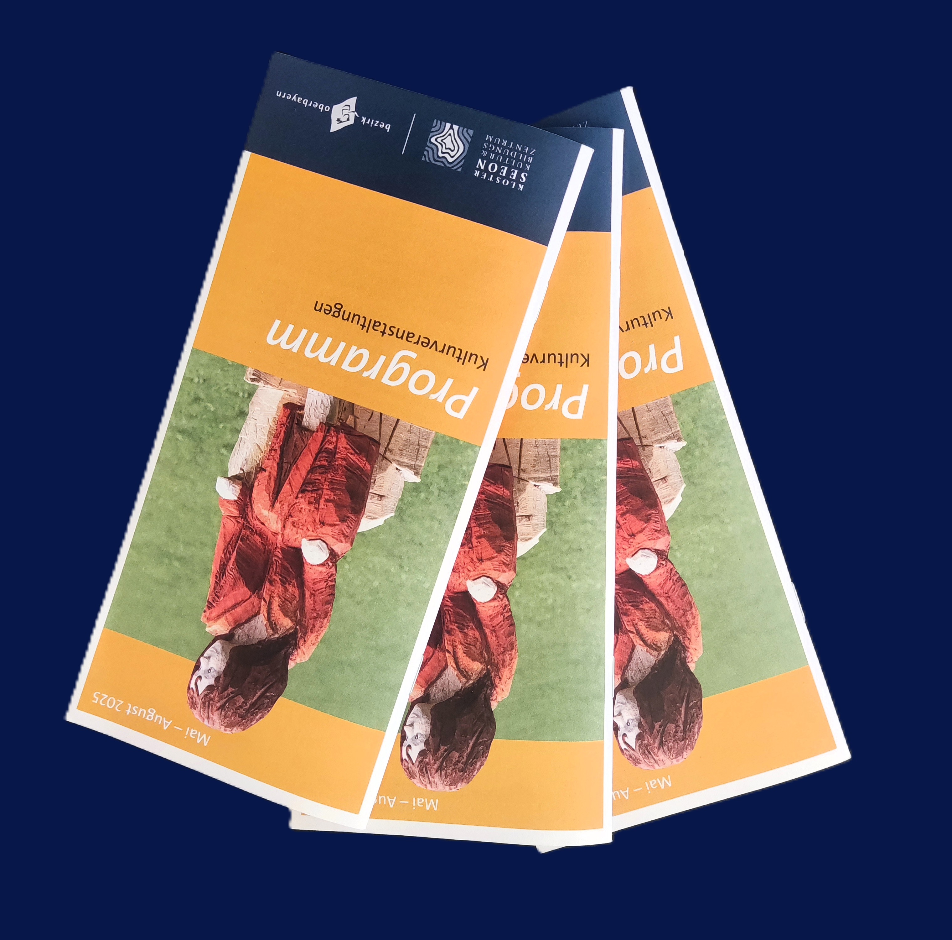 Titelseite des neuen Kulturprogramms von Kloster Seeon mit einer Holzfigur, die Momo darstellt der Schulen für Holz und Gestaltung des Bezirks Oberbayern 