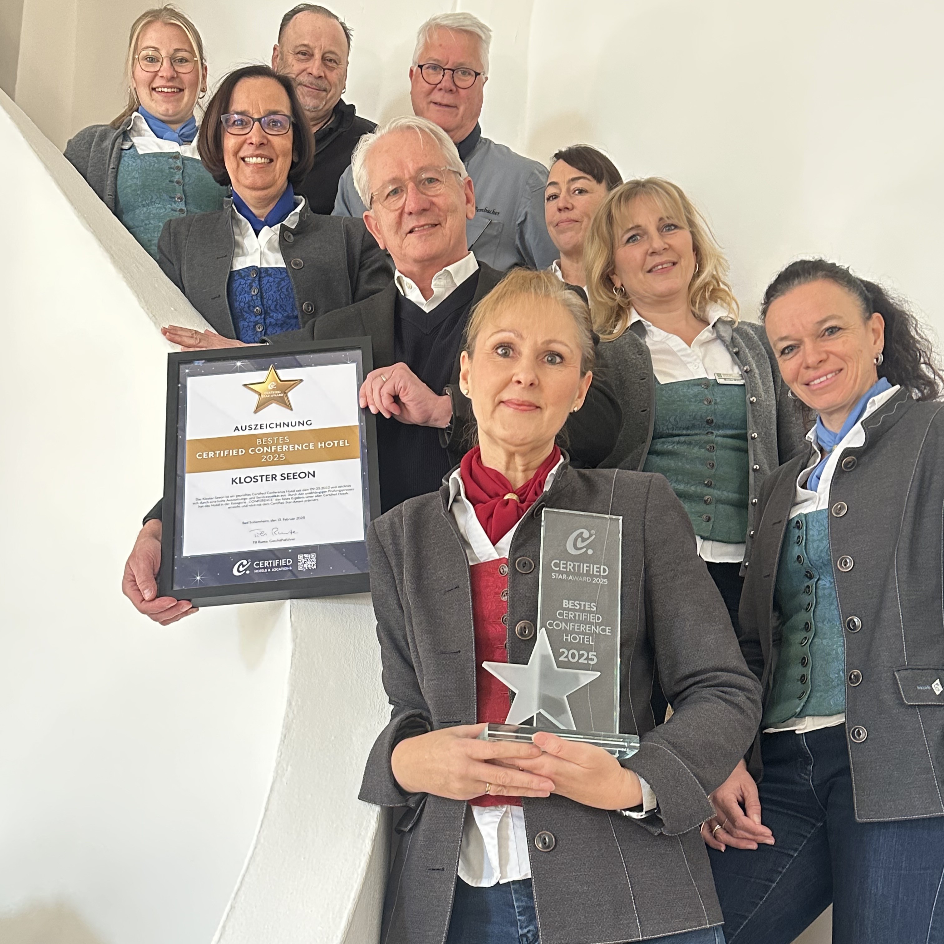 Geschäftsleiter Gerald Schölzel und die Abteilungsleiter von Kloster Seeon stehen im Treppenhaus und präsentieren die Urkunde und den Star-Award  