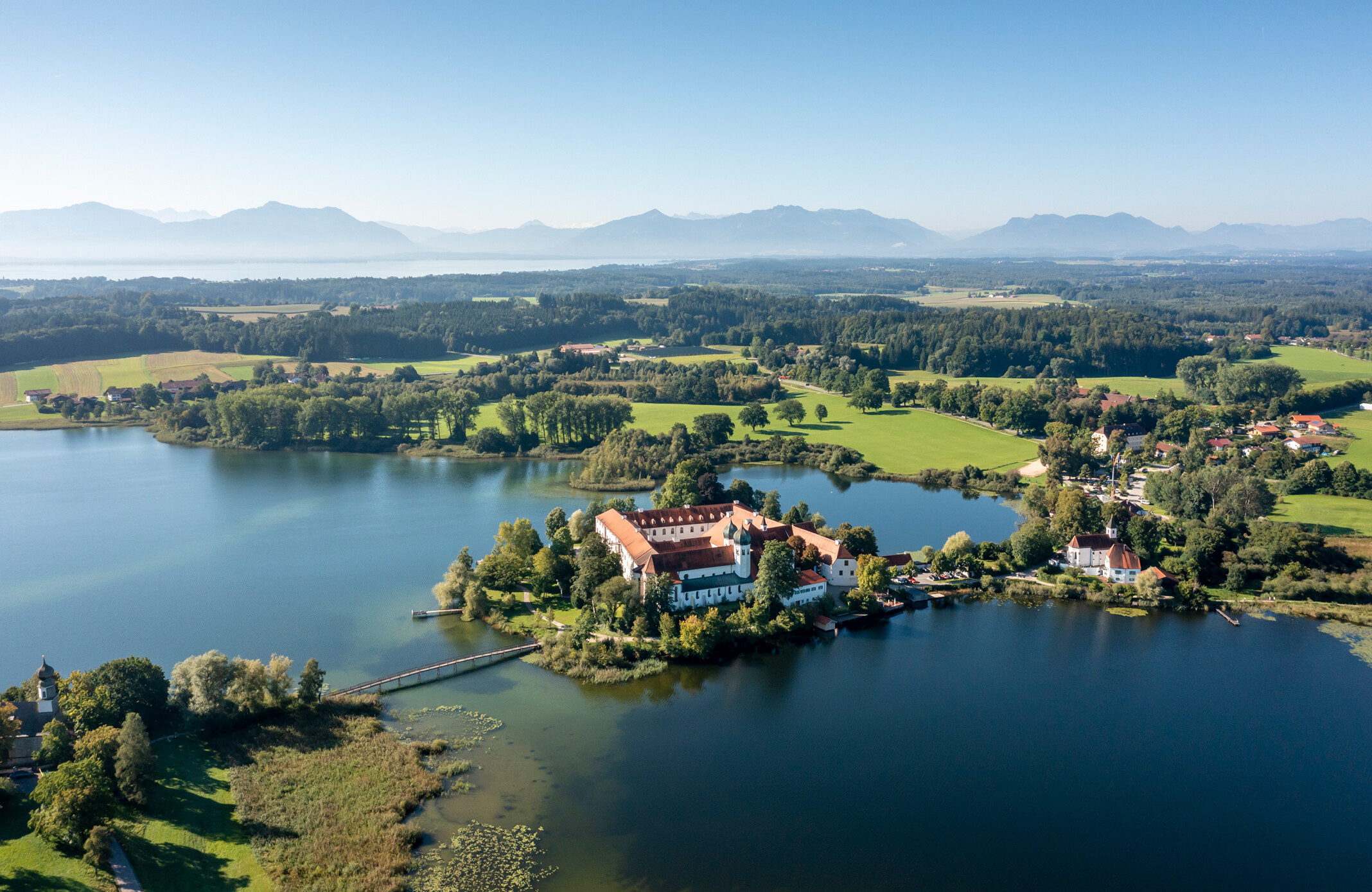Aerial view monastery Kloster Seeon surrounded by the lake and in the background the Chiemgau mountains