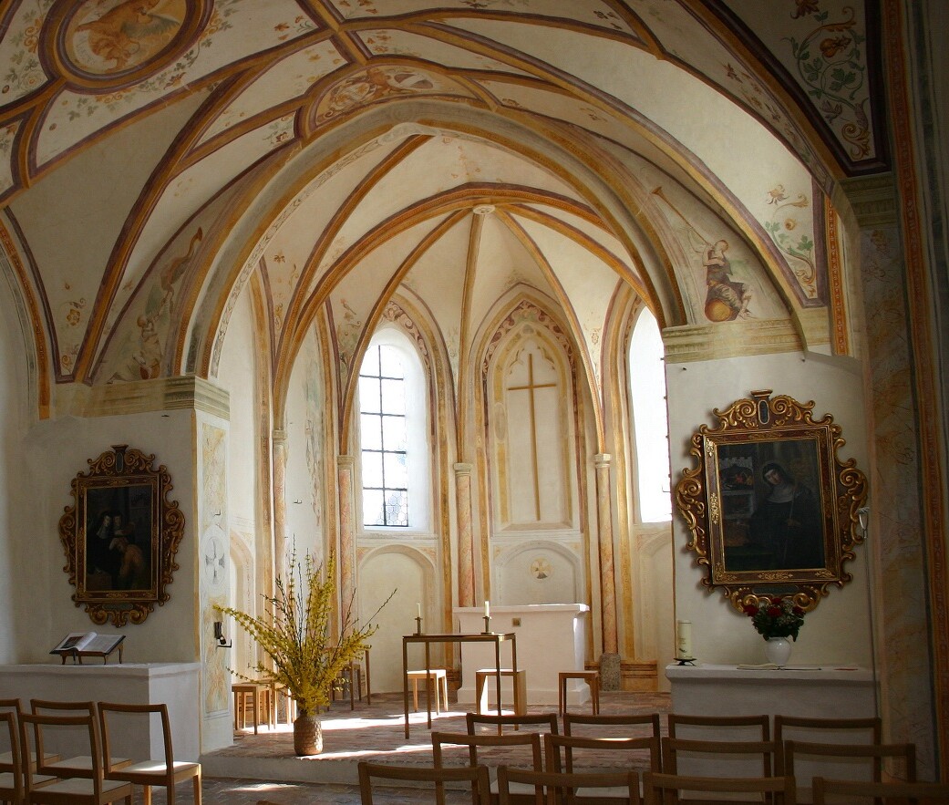 Blick in den Altarraum der heutigen Kirche St. Walburg: Ein gotisches Netzrippengewölbe, im hinteren Breeich zwei Kirchenfenster, durch die das Licht fällt, im Vordergrund Holzstühle