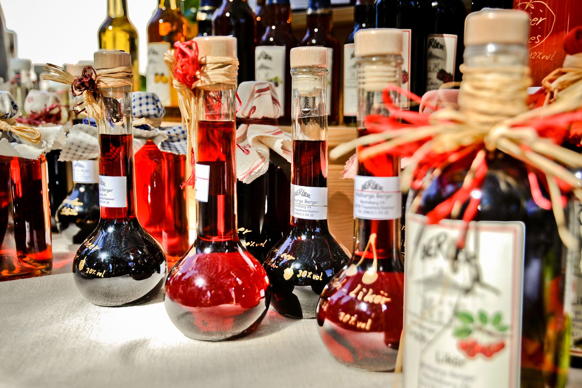 Kleine Glasflaschen gefüllt mit Likör und einer hübschen Schleife aus Bast auf einem Tisch beim Klösterlicher Markt in Kloster Seeon