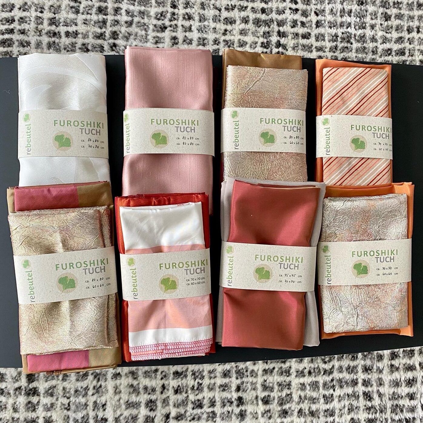 verschiedene eingepackte Tücher in den Farben weiß, rosa und rot von der Firma rebeutel