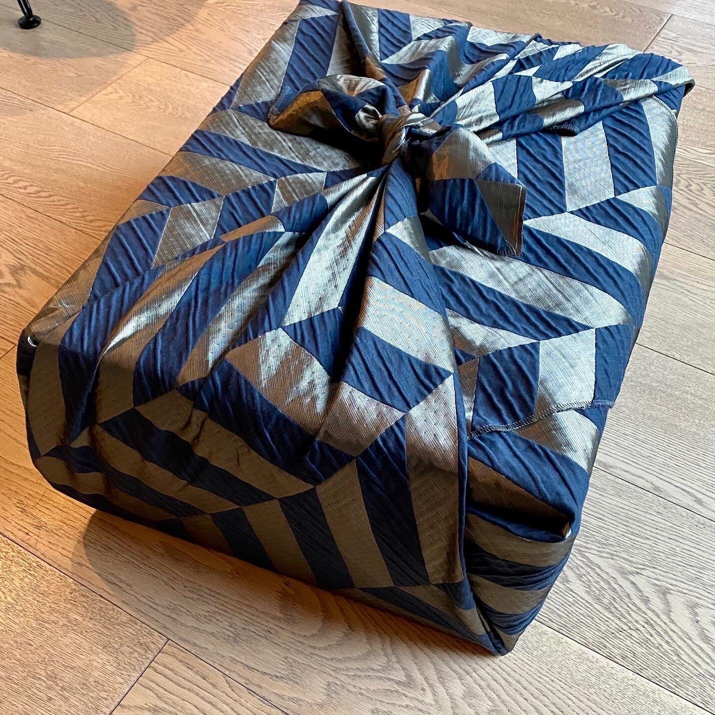 ein mit einem blau-grauem Tuch eingepacktes Geschenk 